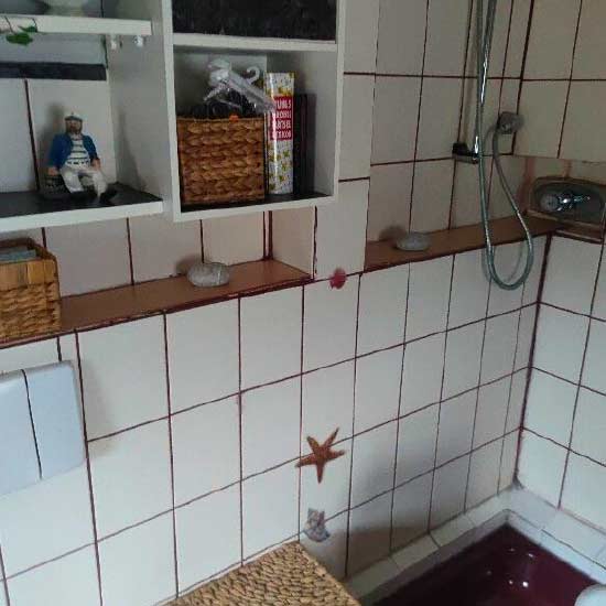 Altes gefliestes Bad mit roten Fugen vor der Sanierung